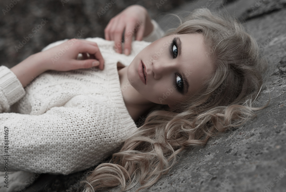 Close up of beautiful young blonde woman with blue eyes in white pullover. .Winter, spring, outdoor portrait. Close up of beautiful young blonde woman with blue eyes in white pullover. .Winter, spring, outdoor portrait.