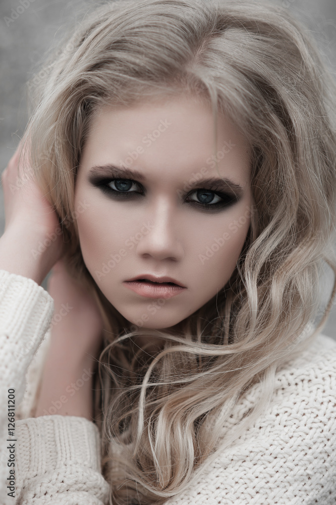 Close up of beautiful young blonde woman with blue eyes in white pullover. .Winter, spring, outdoor portrait. Professional beauty make-up and hair style. Close up of beautiful young blonde woman with blue eyes in white pullover. .Winter, spring, outdoor portrait. Professional beauty make-up and hair style.
