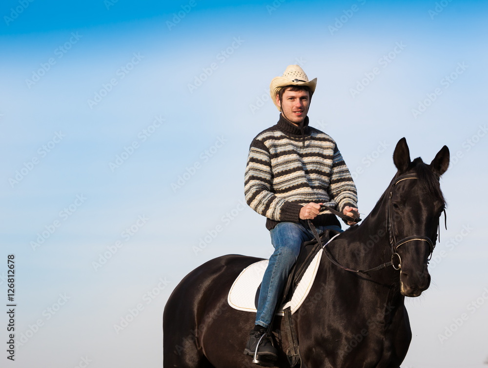Man riding horse, striped pullover, blue jeans, hat, close up