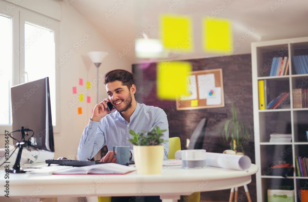 Young man talking on phone in office Young man talking on phone in office