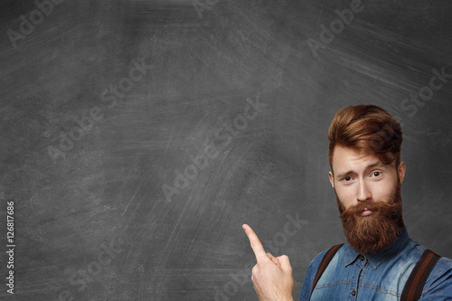 Obraz na plátně Hipster bearded man has idea, pointing his finger up, looking with amused expres