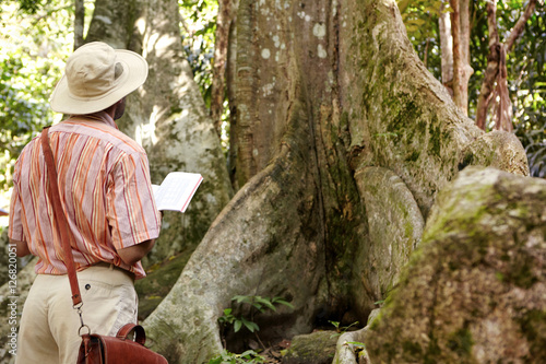 Φωτογραφία Rear view of Caucasian male biologist wearing hat and leather bag exploring jung