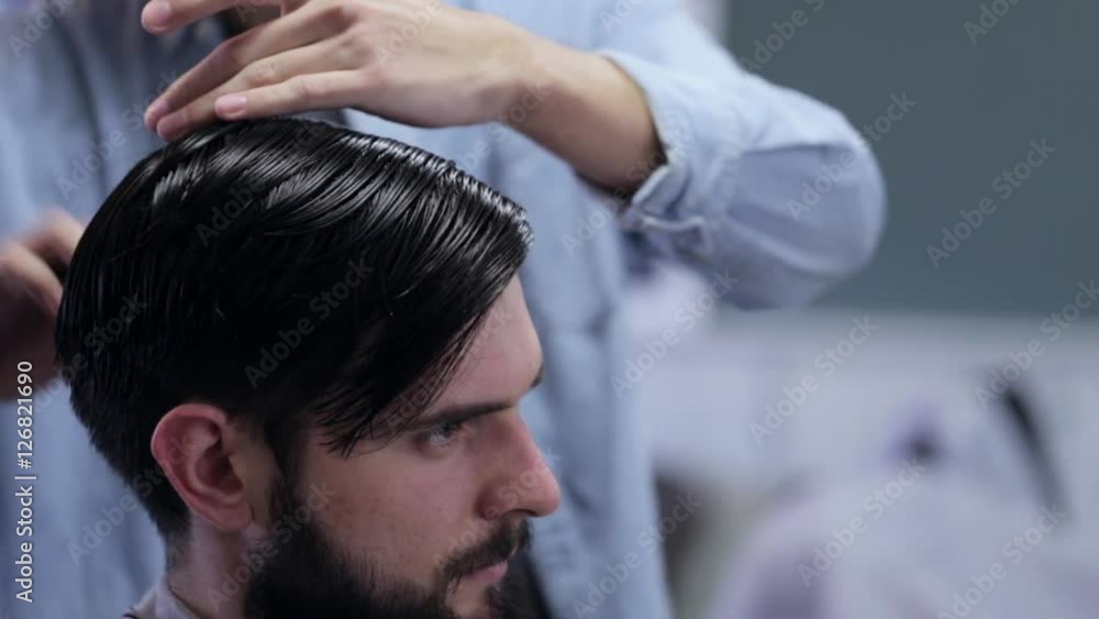 Barber combing the hair of the client before haircut at a barber shop Barber combing the hair of the client before haircut at a barber shop