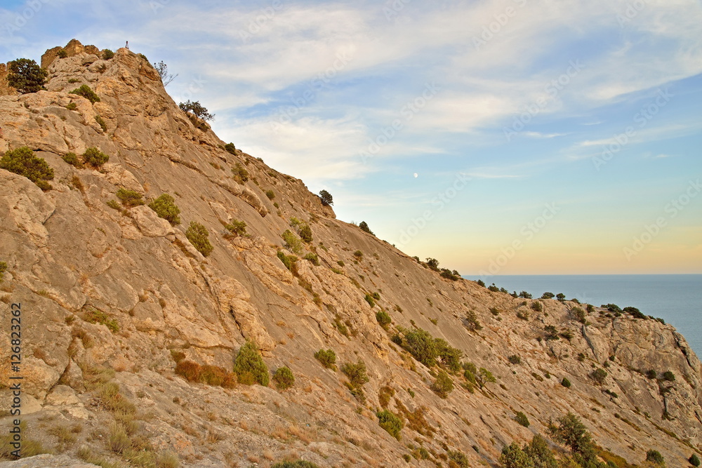 Rocky hillside by the sea at sunset