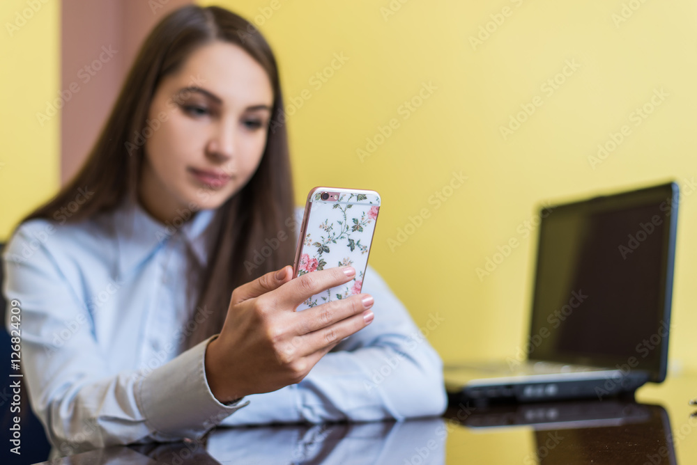 Cute young woman chatting with friend or shopping online with smartphone. Beautiful phone cover with pink flowers. Cute young woman chatting with friend or shopping online with smartphone. Beautiful phone cover with pink flowers.