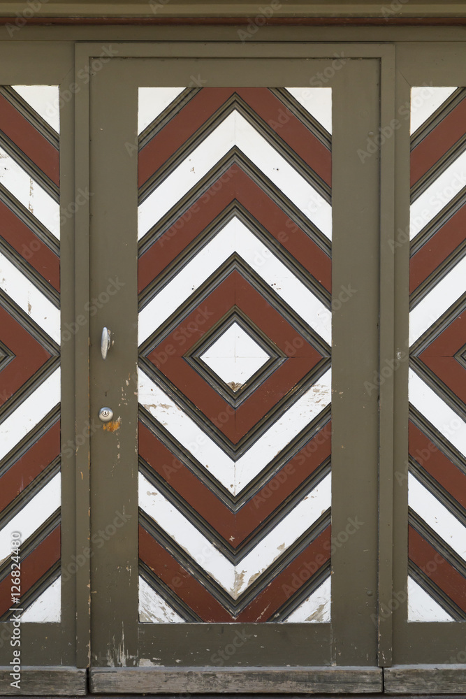 Fototapeta premium A wooden garage door with diamond pattern painted in brown, white and red color