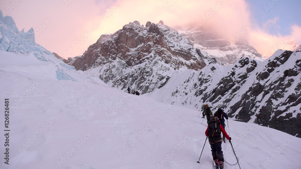 a mountain guide and clients traversing a glacier in the Swiss Alps on a backcountry ski excursion