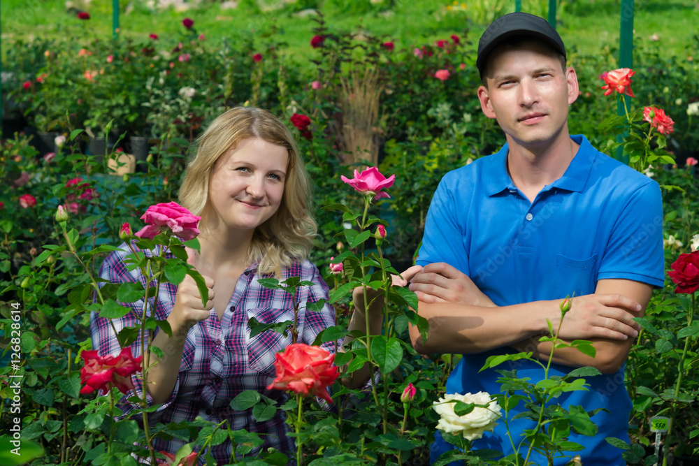 two gardeners are on the background of beautiful roses