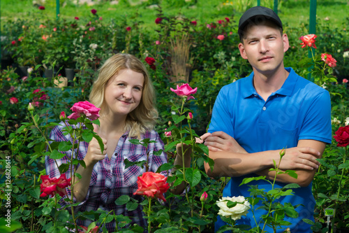two gardeners are on the background of beautiful roses