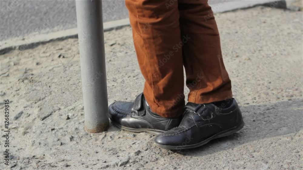 Boy feet on concrete/foot boy waiting on the concrete at the bus stop Boy feet on concrete/foot boy waiting on the concrete at the bus stop