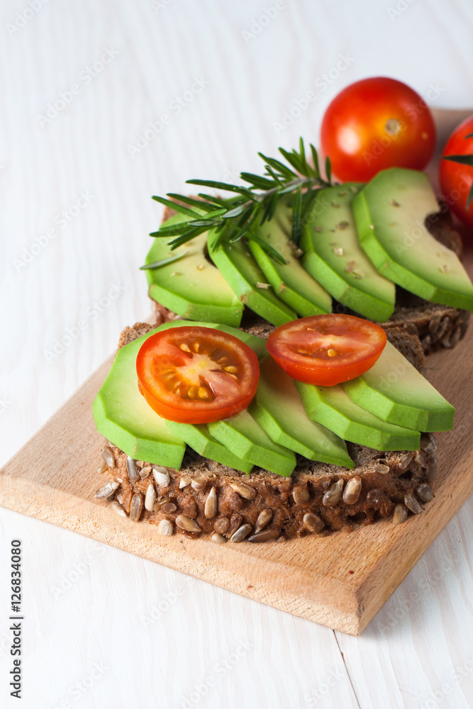 Avocado toast, cherry tomato on wooden background. Breakfast with toast avocado, vegetarian food, healthy diet concept.