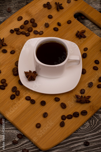 Small white cup of coffee  star anise on wooden background