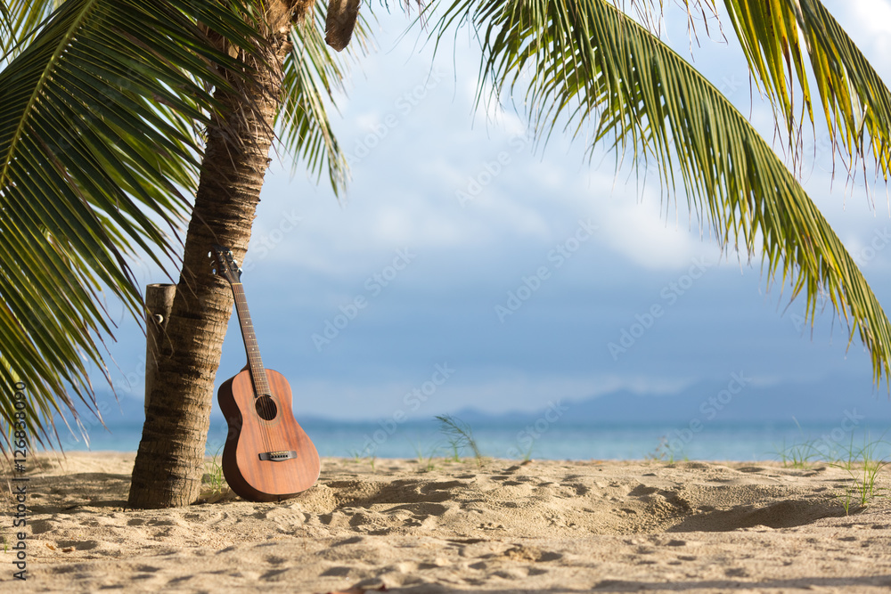 An acoustic guitar standing in the sandy beach under palm tree Stock ...