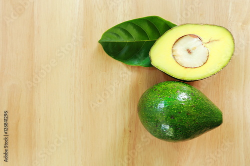 Fresh avocado fruits on a wood background.