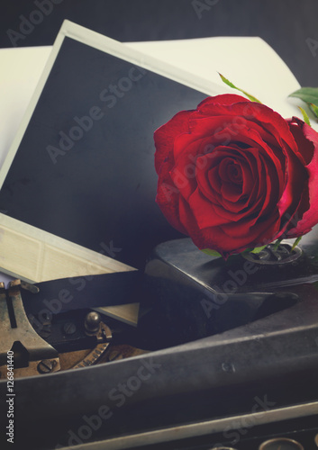 fresh red rose on vintage typewriter with instant phoro, retro toned photo