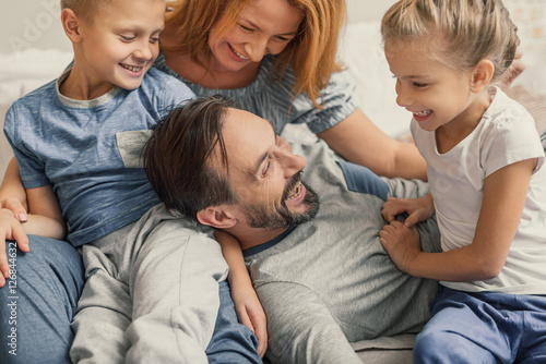 Photos Happy family lying down on bed at home