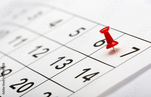 Pin on the date. The seventh day of the month is marked with a red thumbtack. Focus point on the red pin.