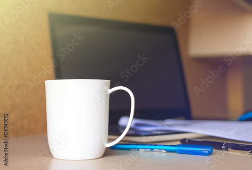 Mug coffee on table with laptop pen and paper.