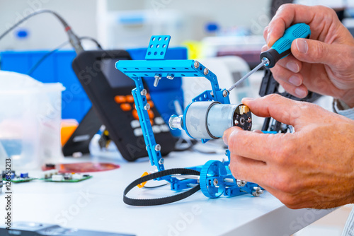 Robotics development closeup. Electronics engineer or programmer hands with special tools working with robot arm. Modern technologies. DIY Hobby Concept photo