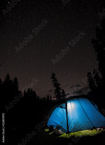 A starry night sky high in the mountains and a tent.