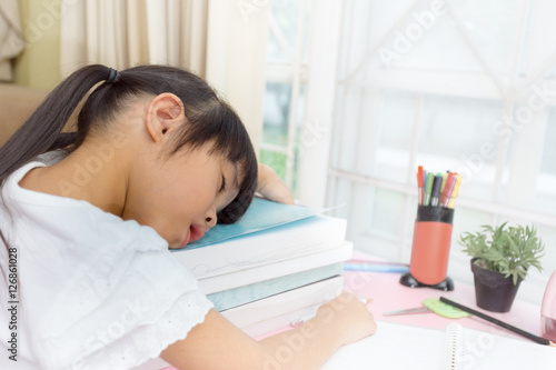 Educational theme: schoolgirl sleeping on her textbooks in home