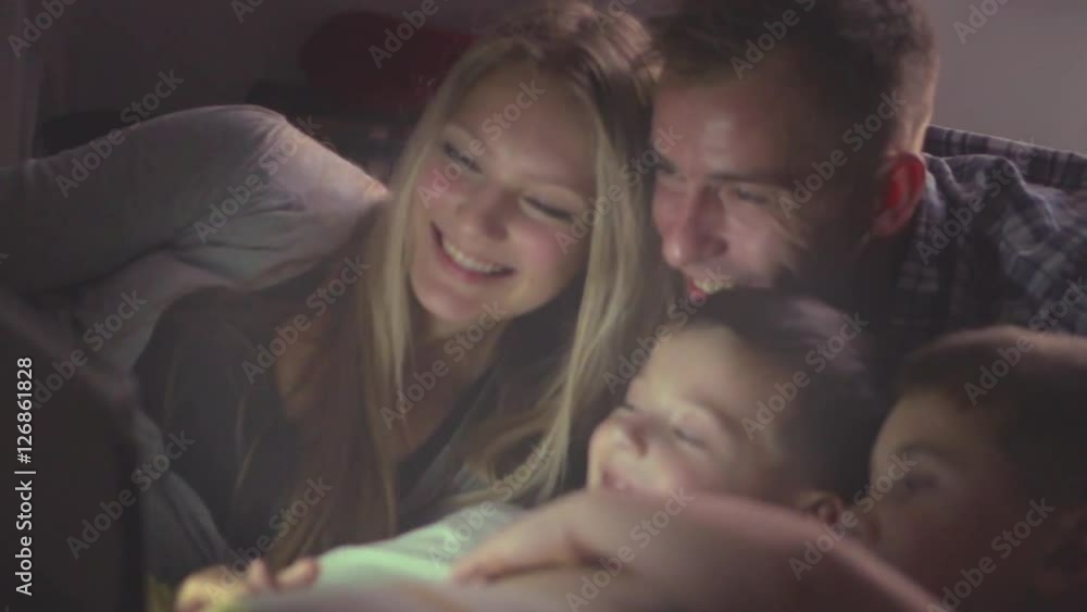 Happy family watching movie on tablet pc in a dark room. Full HD 1080p, slow motion 240 fps Happy family watching movie on tablet pc in a dark room. Full HD 1080p, slow motion 240 fps