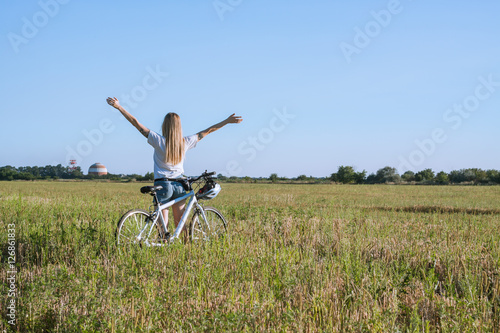 Young woman with bicycle rising hands