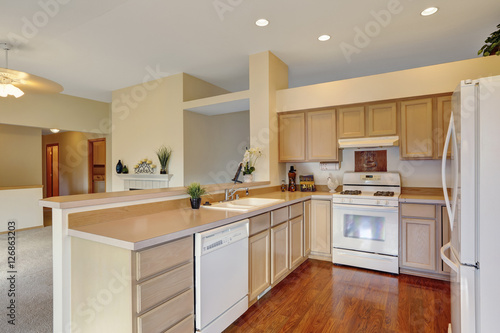 Kitchen in creamy tones with hardwood floor and white appliances