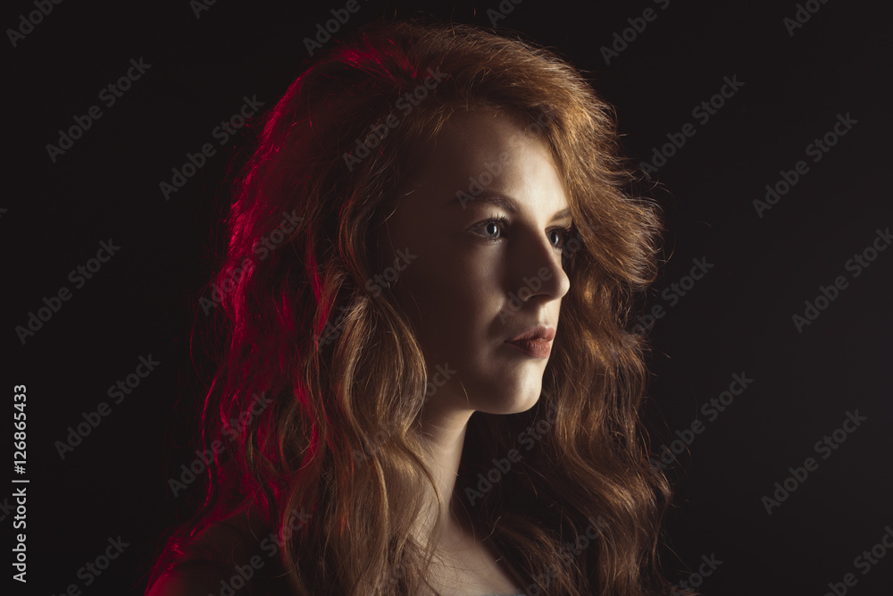 Fototapeta premium Luxurious woman with shadow on her face and red light