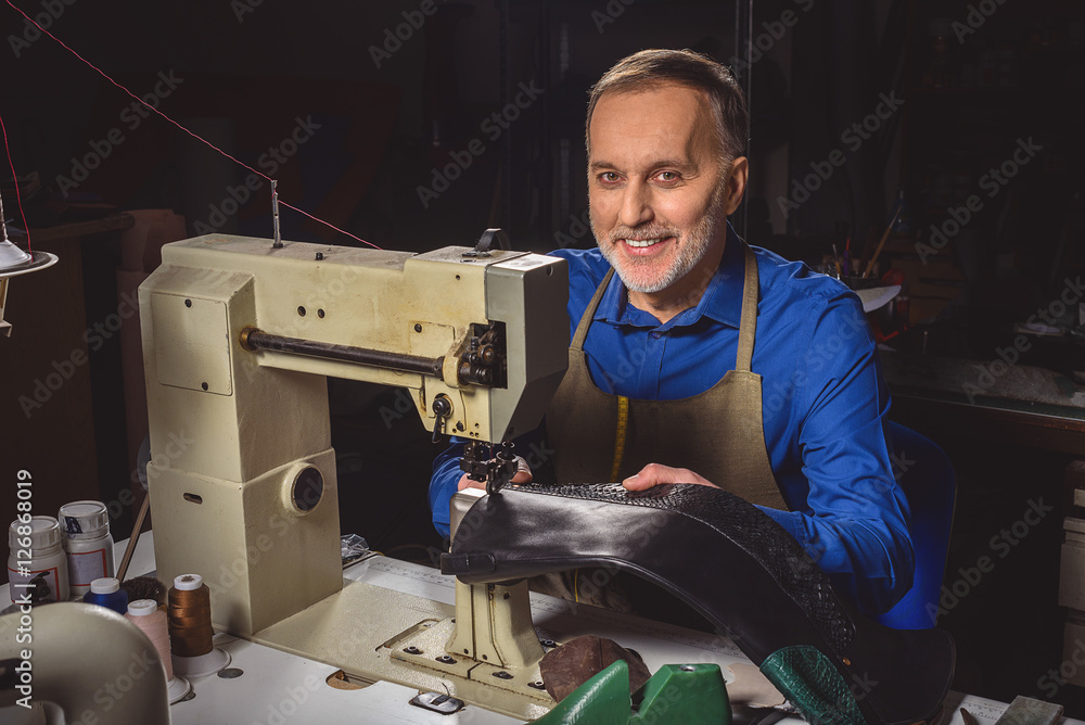 happy shoemaker sitting at the sewing machine