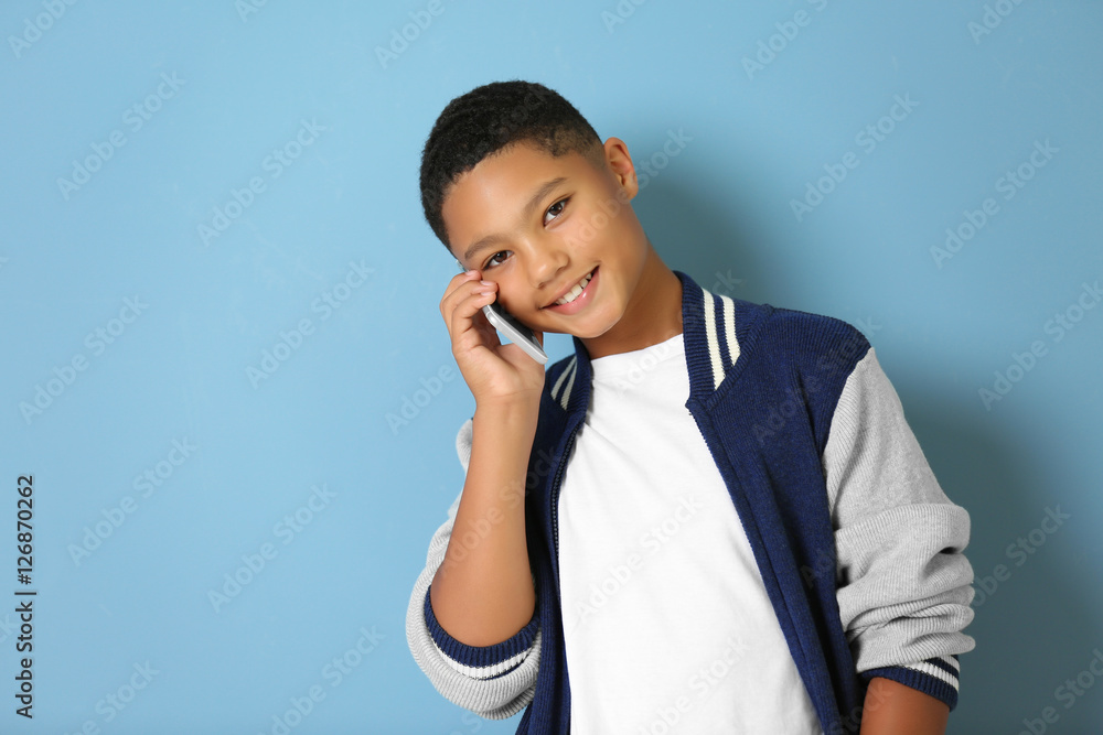 African American boy with cellphone on blue background African American boy with cellphone on blue background