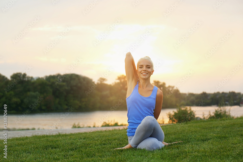 Young beautiful woman practicing yoga on grass near pond Young beautiful woman practicing yoga on grass near pond