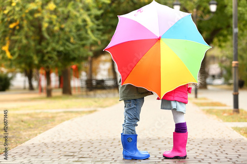 Children hiding behind colorful umbrella in park
