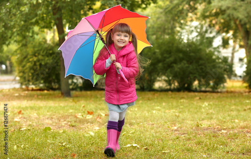 Funny girl with colorful umbrella in park