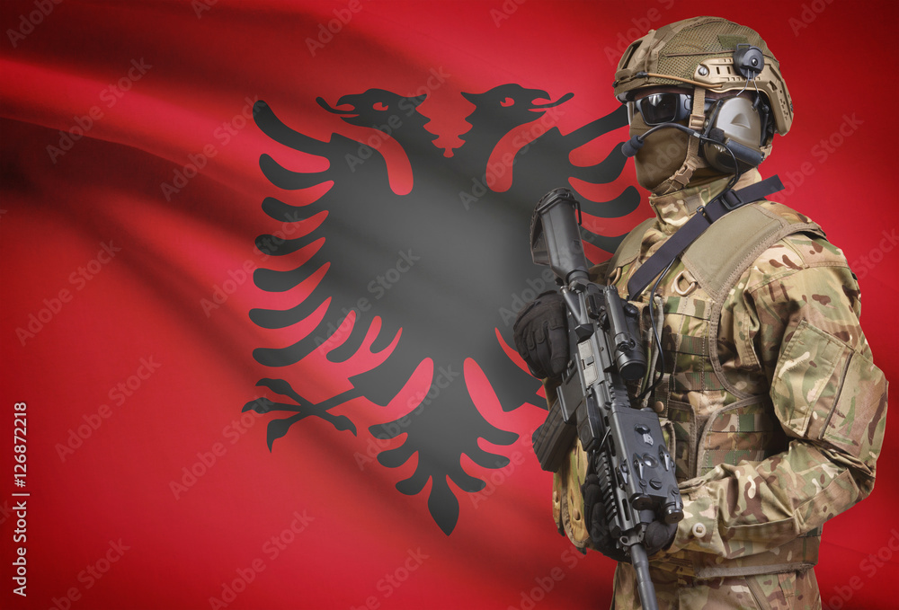 Soldier in helmet holding machine gun with flag on background series - Albania Soldier in helmet holding machine gun with flag on background series - Albania