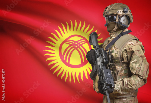 Soldier in helmet holding machine gun with flag on background series - Kyrgyzstan