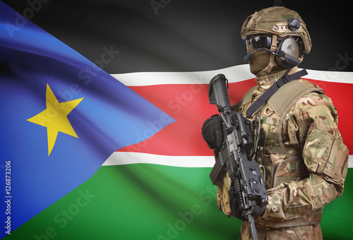 Soldier in helmet holding machine gun with flag on background series - South Sudan