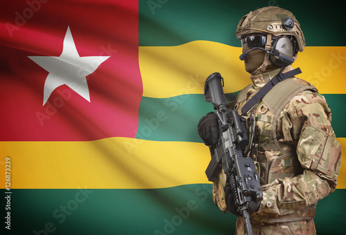Soldier in helmet holding machine gun with flag on background series - Togo