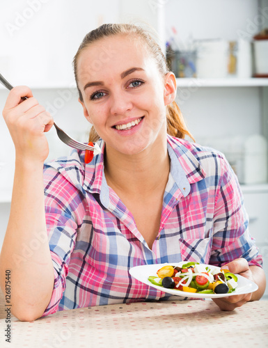 portrate of young woman eating salad at kitchen