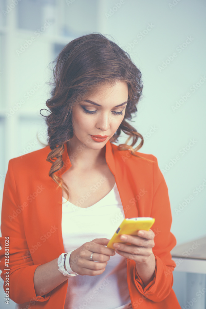 Beautiful businesswoman using cell phone standing in office Beautiful businesswoman using cell phone standing in office