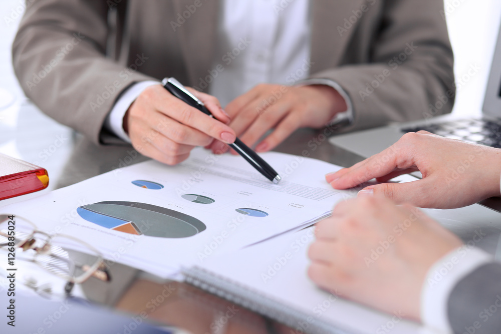 Group of business people at meeting discussing financial results. Women pointing into laptop computer monitor Group of business people at meeting discussing financial results. Women pointing into laptop computer monitor