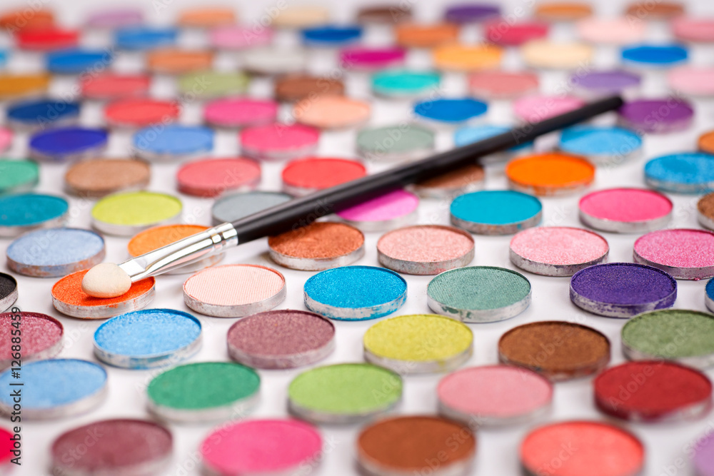 Cosmetic brush laying over large group of eyeshadows Cosmetic brush laying over large group of eyeshadows