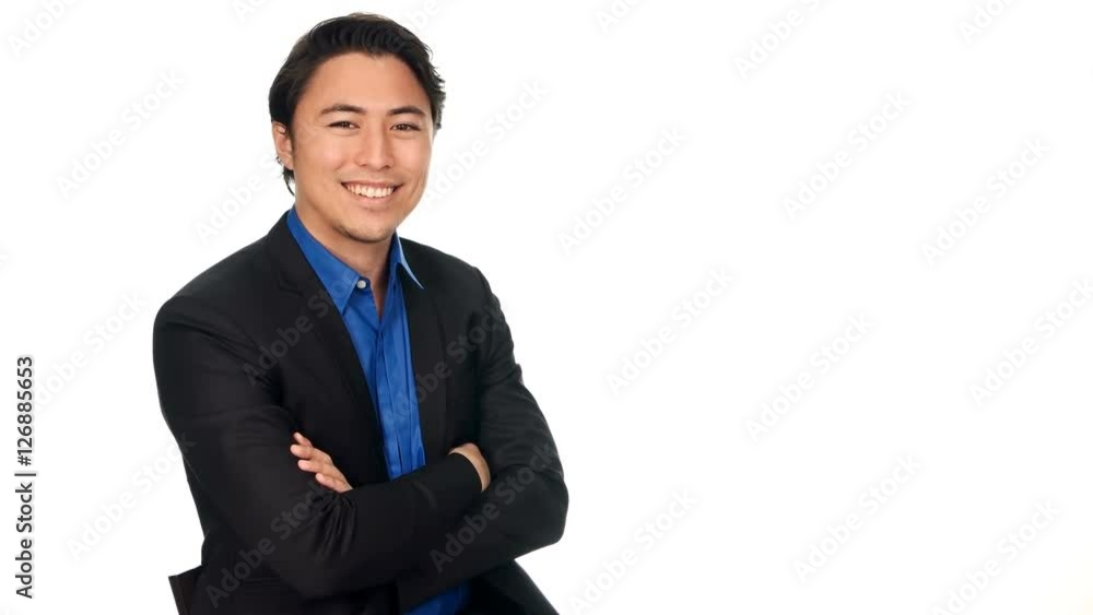 Handsome businessman in a blue shirt and black suit sitting down against a white background with his arms crossed doing thumbs up. Handsome businessman in a blue shirt and black suit sitting down against a white background with his arms crossed doing thumbs up.