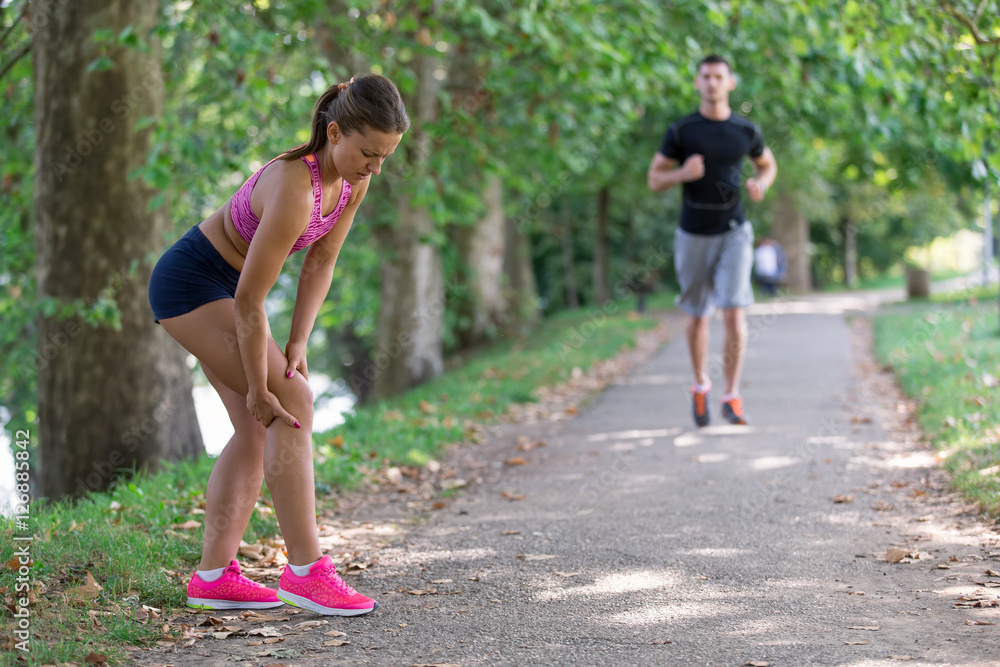 Fototapeta premium Man helps to woman with injured knee at sport activity