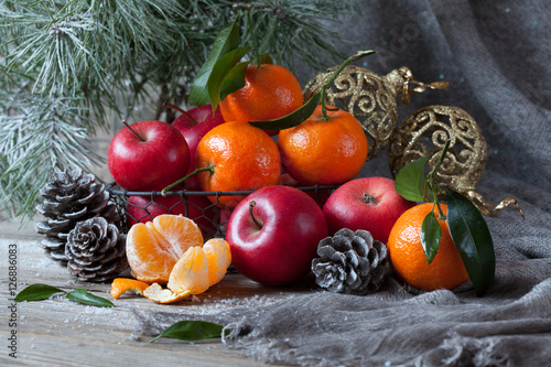 Red apples, mandarins and pine cones on a table