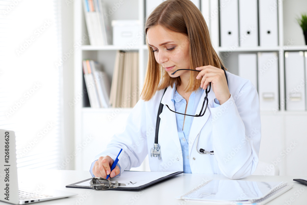 Female doctor writing a medical prescription at clipboard Female doctor writing a medical prescription at clipboard