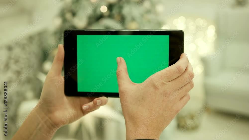 Close-up of female hands touching green screen on tablet Green screen Chroma Key. Close up. Tracking motion. Vertical.with blur christmas decoration background Close-up of female hands touching green screen on tablet Green screen Chroma Key. Close up. Tracking motion. Vertical.with blur christmas decoration background