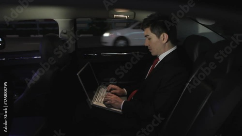 MH Businessman Sitting in Back Seat of Car Working on Laptop at Night / Singapore
