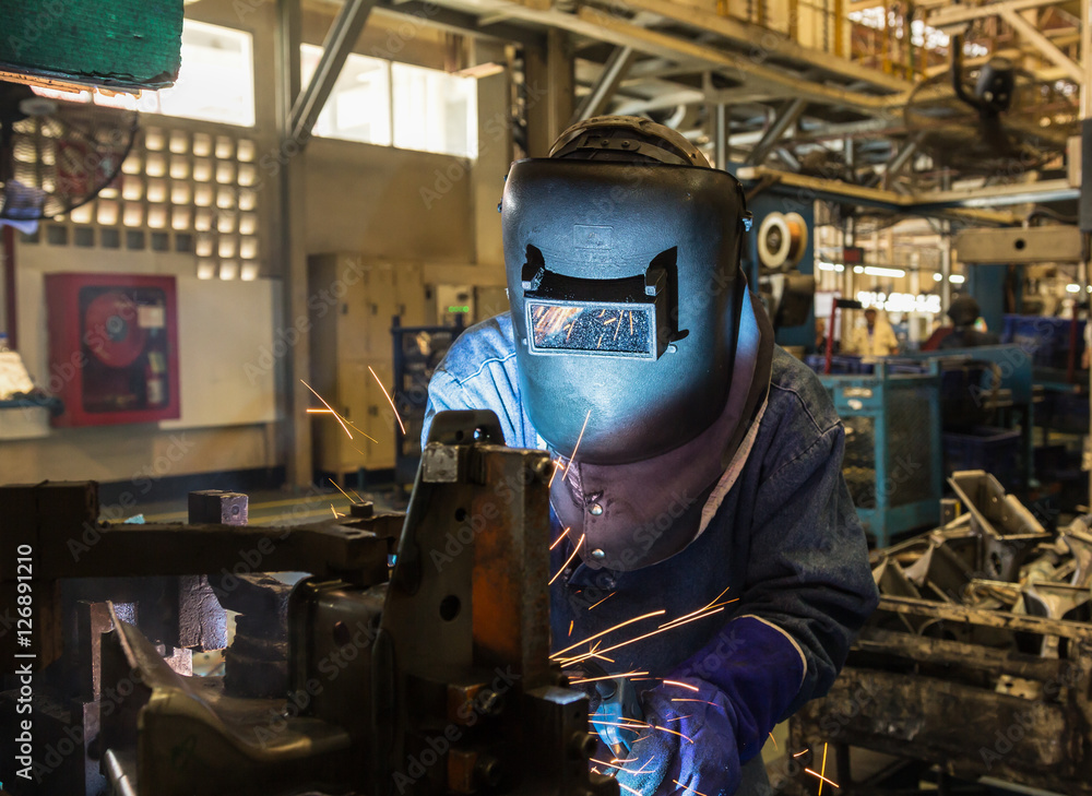 Welder working a welding metal with protective mask in car factory Welder working a welding metal with protective mask in car factory