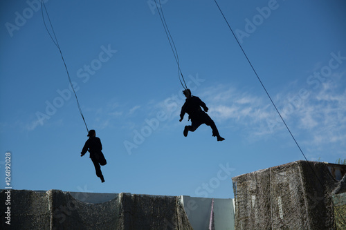Men and women flying in sky with safety rope.